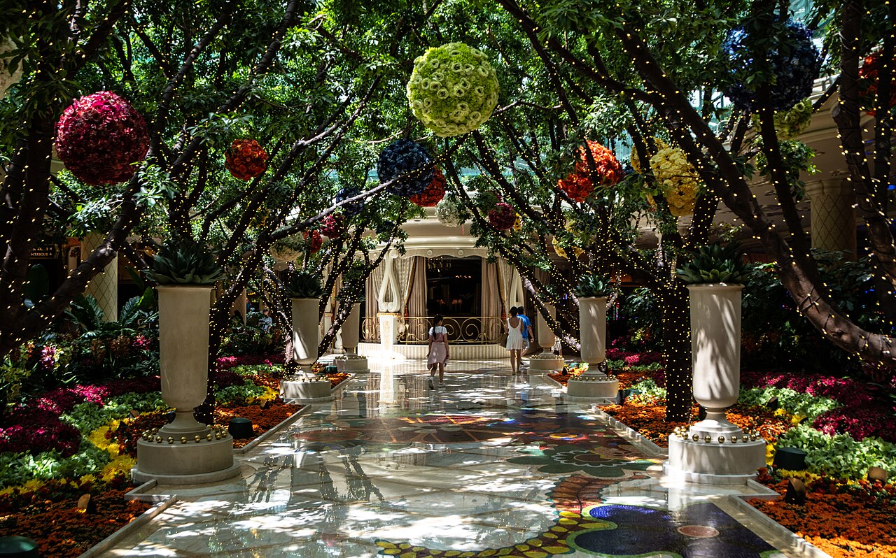 Wynn atrium with hanging flower balls, planted urns and a floral mosaic floor; no bear sculpture is visible.