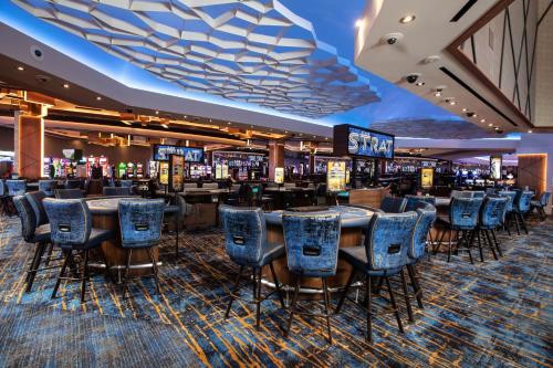 Table games and blue chairs beneath the STRAT sign on the casino floor.
