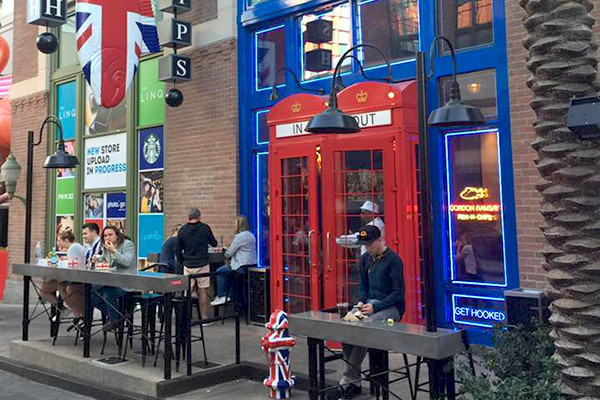 The red telephone-box-style entrance and outdoor seating at Gordon Ramsay Fish & Chips on the LINQ Promenade.
