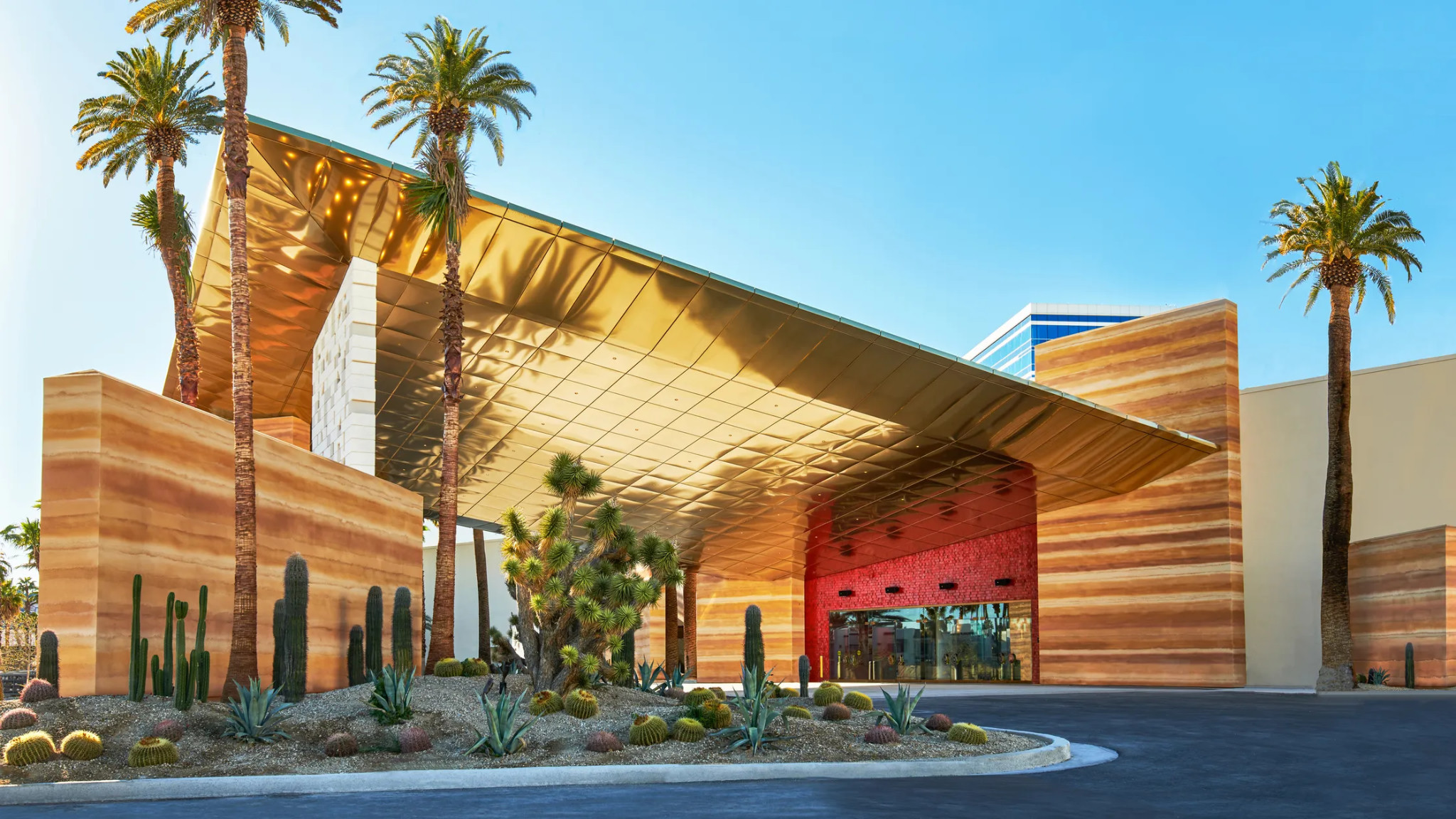 Virgin Hotels Las Vegas entrance with a gold-toned canopy and desert landscaping.