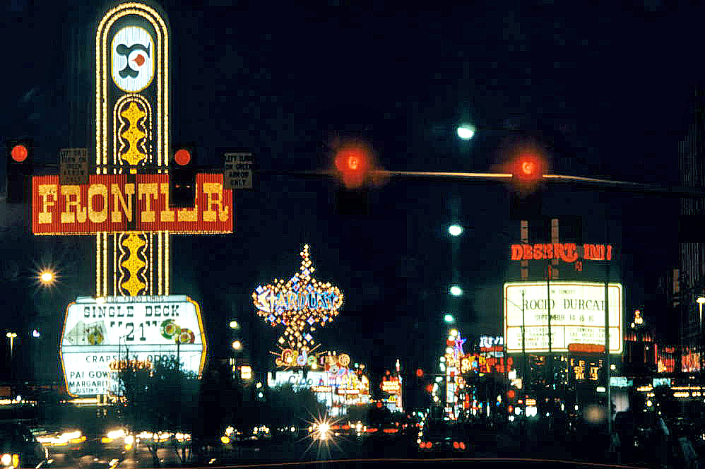 The Frontier’s neon sign at left and the Stardust sign farther along the Strip at night.