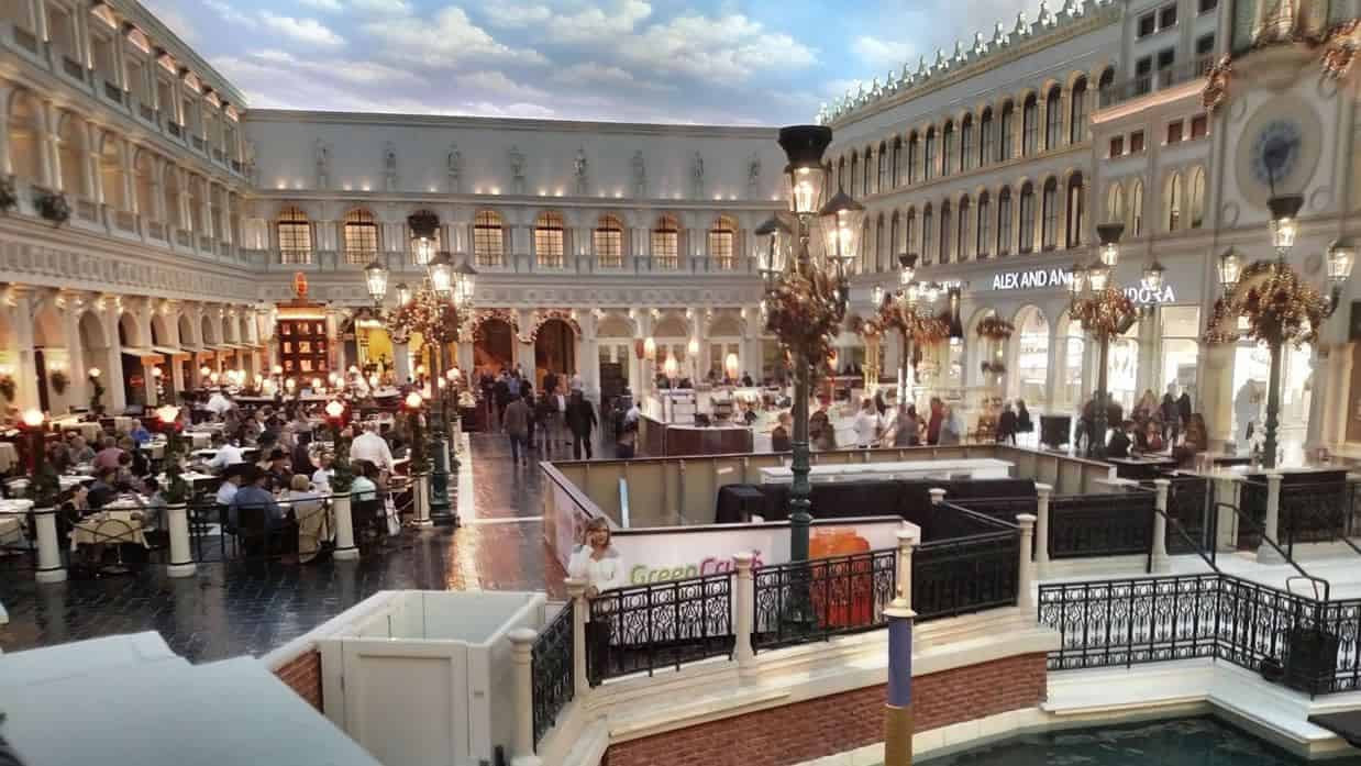 The indoor square with café tables, decorative street lamps and a painted sky.
