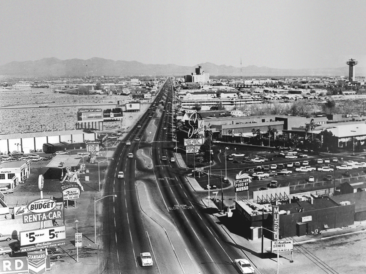 Historical Strip view showing Musso’s restaurant and its signs in the lower-right foreground; photograph date unknown.
