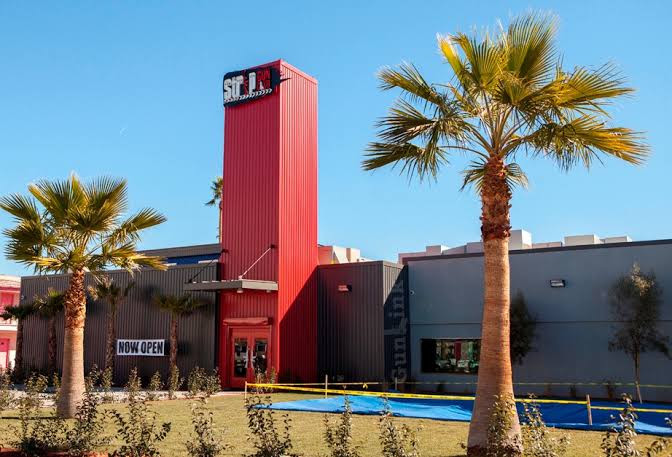 The Strip Gun Club exterior, with its red entrance tower and palm trees.