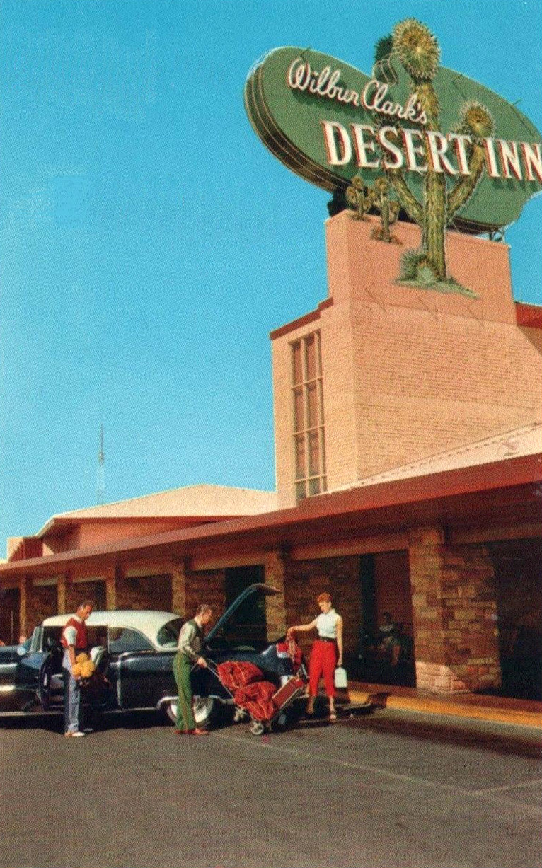 Desert Inn frontage with its Wilbur Clark sign, palm tree, a parked car and visitors.