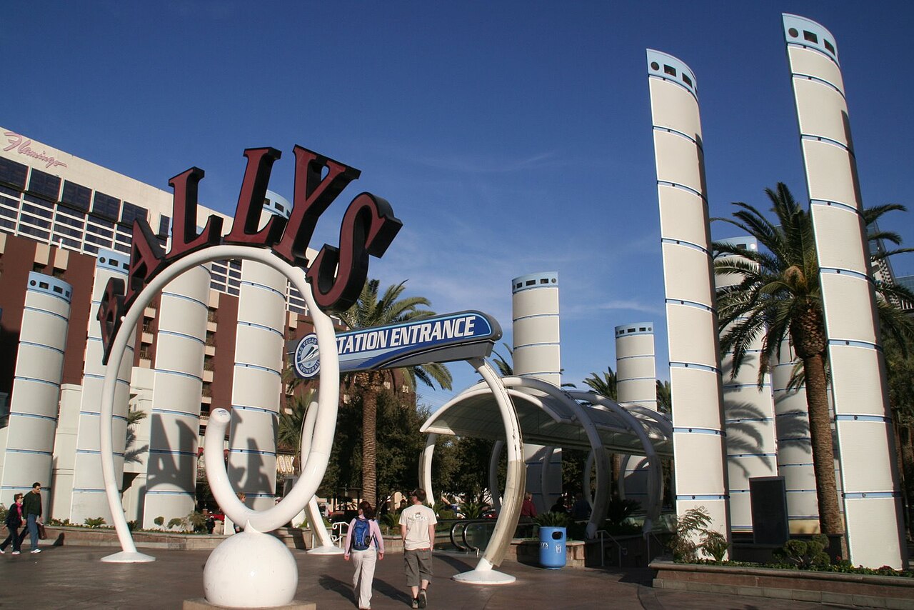 The former Bally’s entry sign and covered moving walkway, framed by white columns and palms.