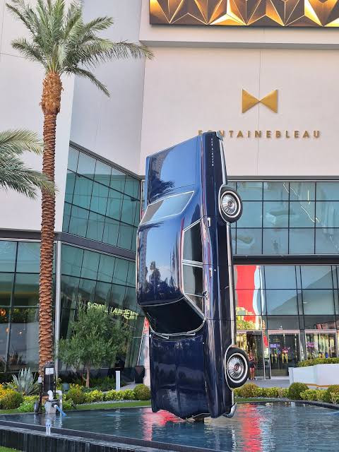 An upright blue car sculpture in the fountain outside Fontainebleau Las Vegas.