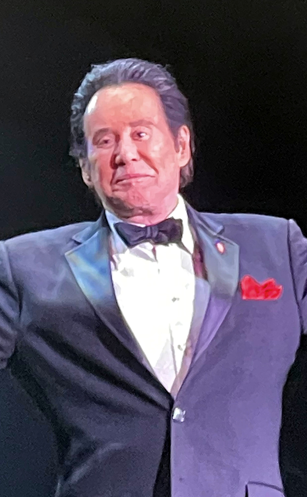 Wayne Newton in a dark tuxedo with a red pocket square.