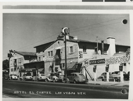 Black-and-white street view of El Cortez, with its corner hotel sign and parked cars.