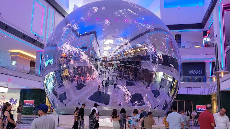 The large reflective Globe in Resorts World’s shopping interior, with visitors gathered around its base.