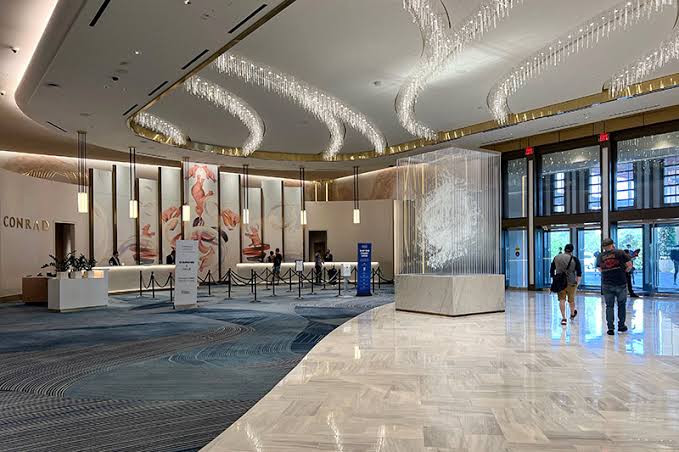 The Conrad lobby at Resorts World, with reception desks, floral wall panels and sweeping ceiling lights.