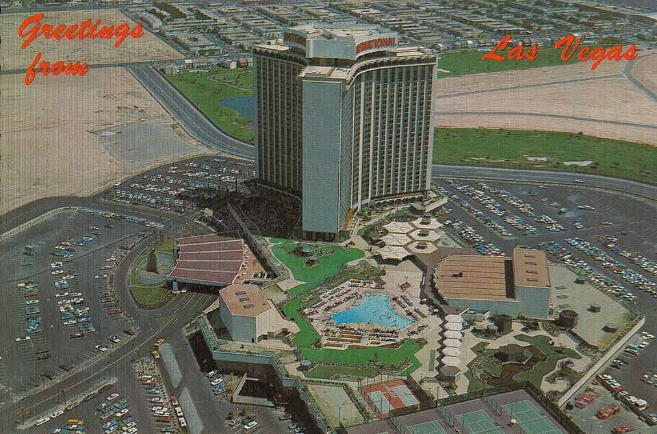 Historical postcard showing the International Hotel tower, pool and surrounding grounds.