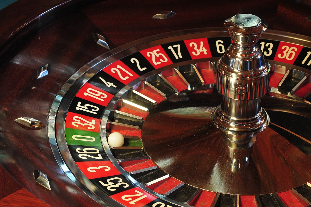 A roulette wheel shows one green zero among red and black numbered pockets.
