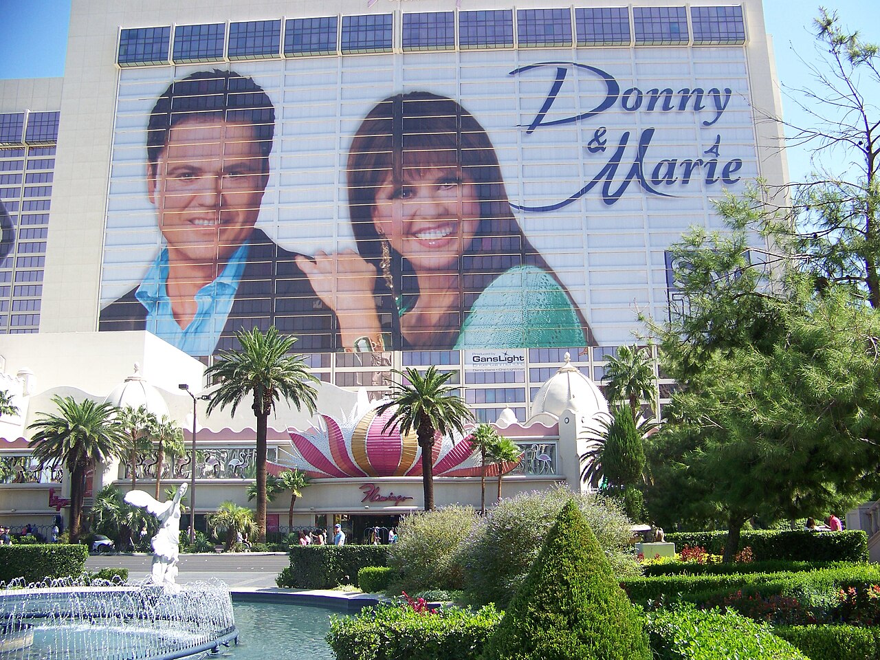 A large Donny and Marie portrait banner covers the hotel facade above the plume and landscaped frontage.