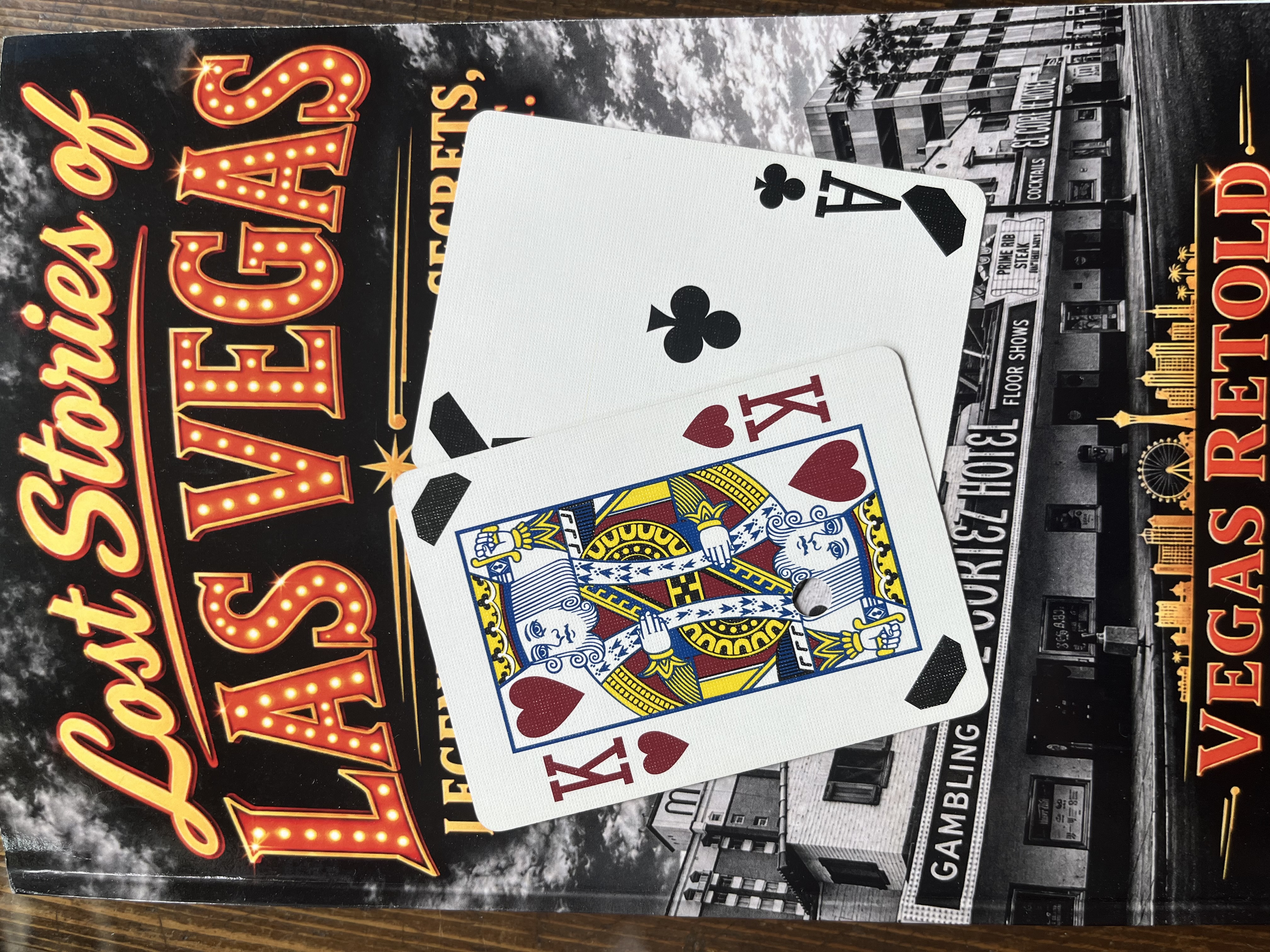 King of hearts and ace of clubs with black corner markings on a Lost Stories of Las Vegas book.