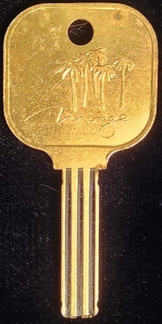 Gold-coloured Mirage key stamped with palm trees and the Mirage name.