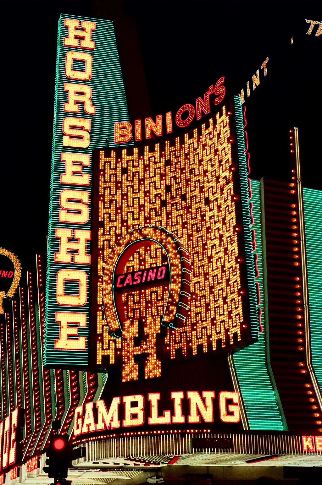 Illuminated Binion's Horseshoe signs above the casino frontage at night, with partial Mint lettering to the right.