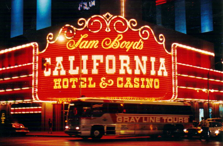 Red and gold Sam Boyd’s California Hotel and Casino entrance sign glowing above a passing tour bus at night.