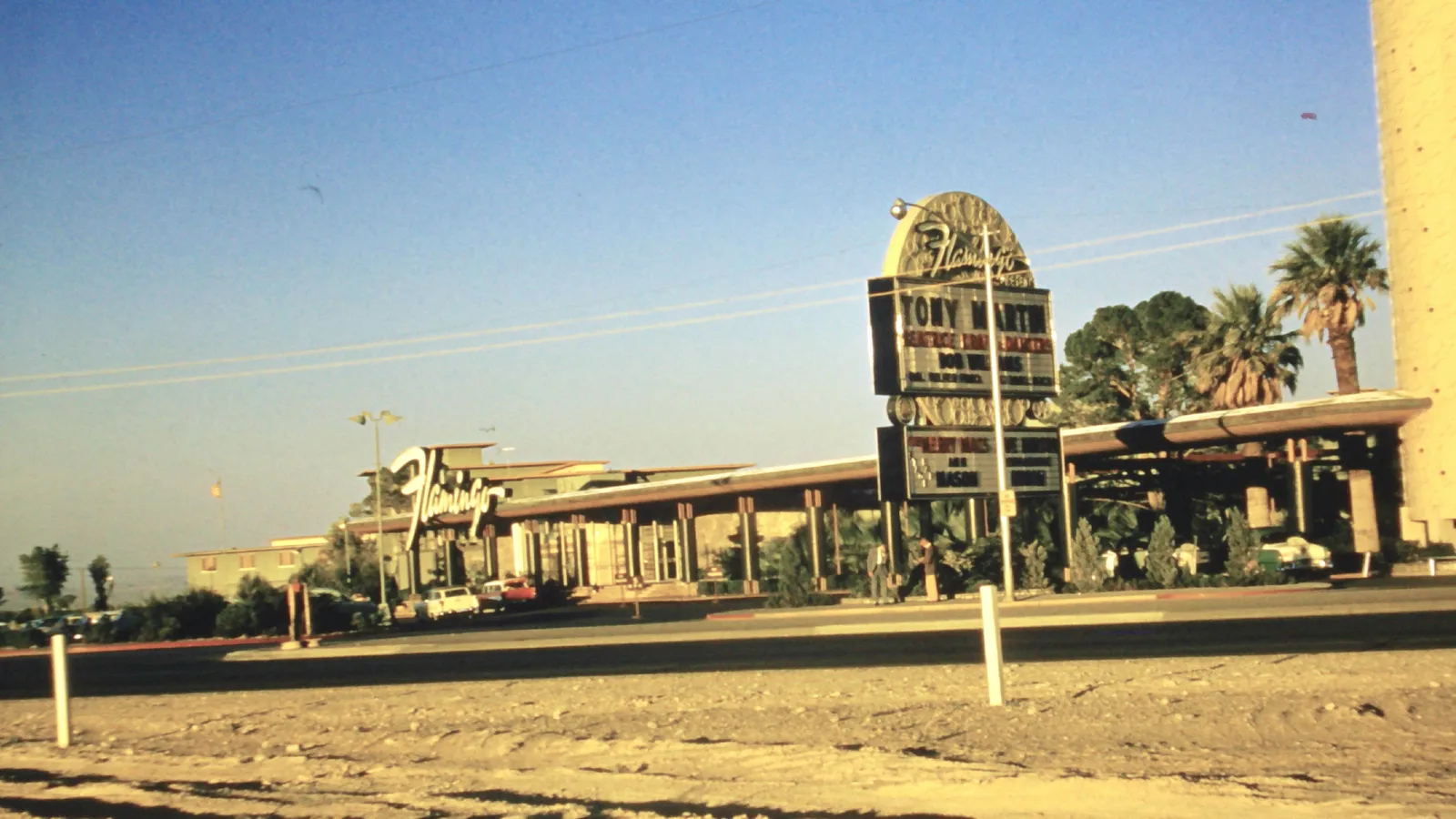 Low-rise Flamingo frontage across the road, with palm trees, parked cars and a marquee advertising Tony Martin, in a photograph cataloged as 1957.