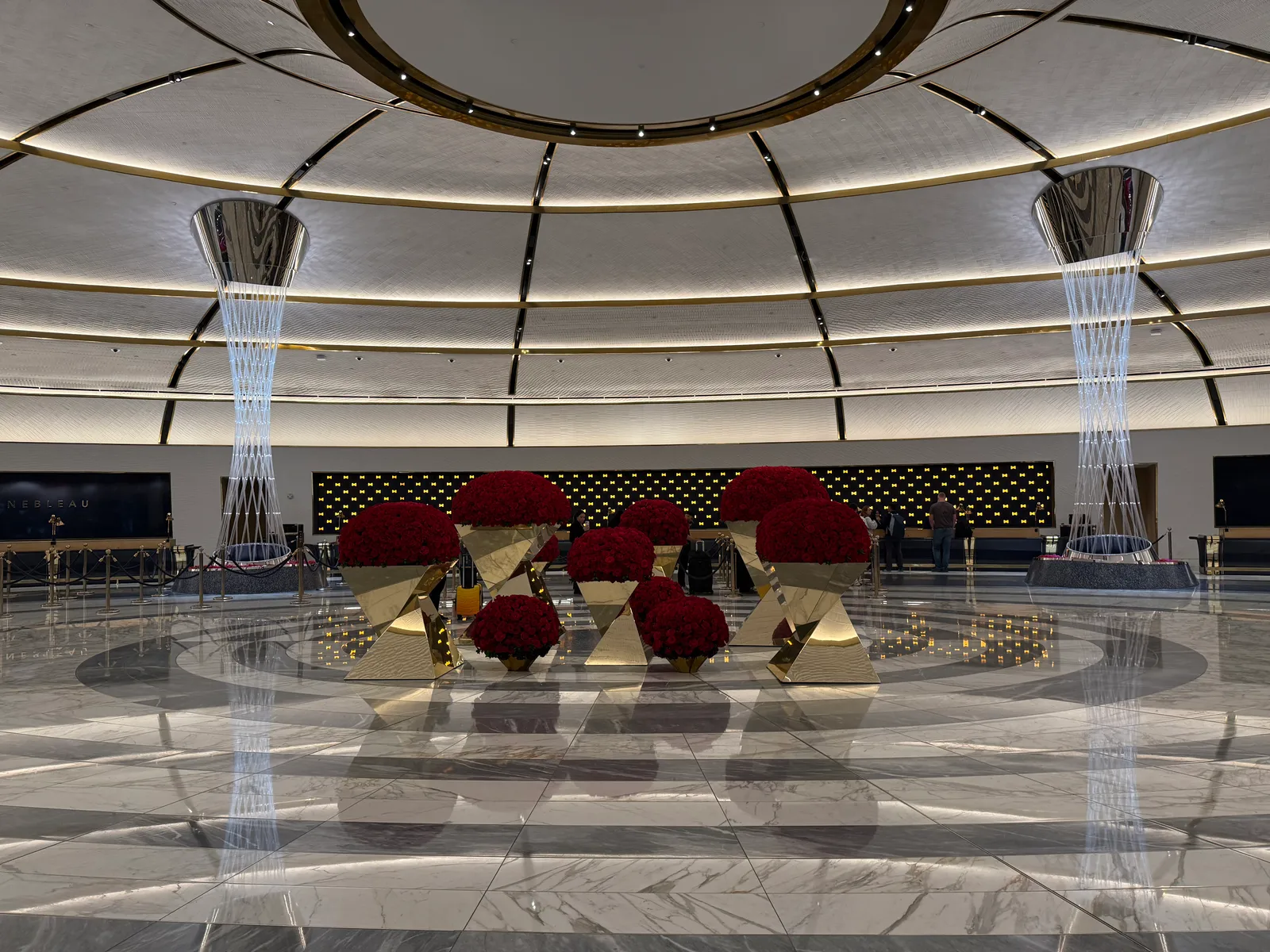 Red floral arrangements, sculptural columns and a registration counter beneath a circular patterned ceiling in Fontainebleau’s lobby.