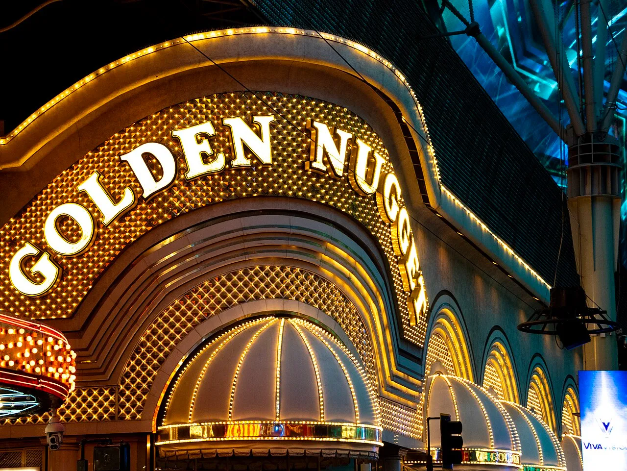 Illuminated Golden Nugget lettering and gold arches beneath the blue Fremont Street Experience canopy.