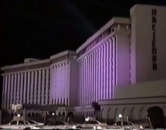 White Hacienda hotel tower illuminated at night, seen in a low-resolution historical video still.