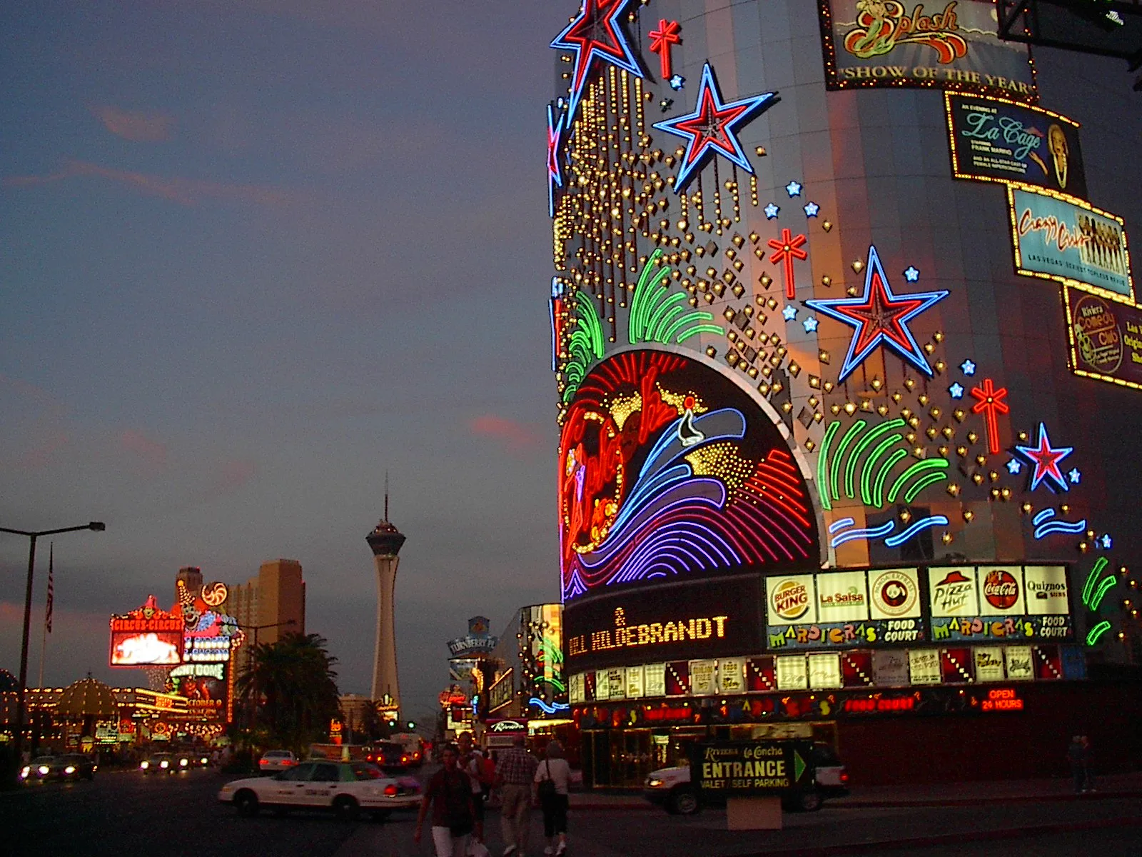 Illuminated Riviera frontage and signs for shows and dining at night in 2003, with Circus Circus and the Stratosphere visible farther along the Strip.