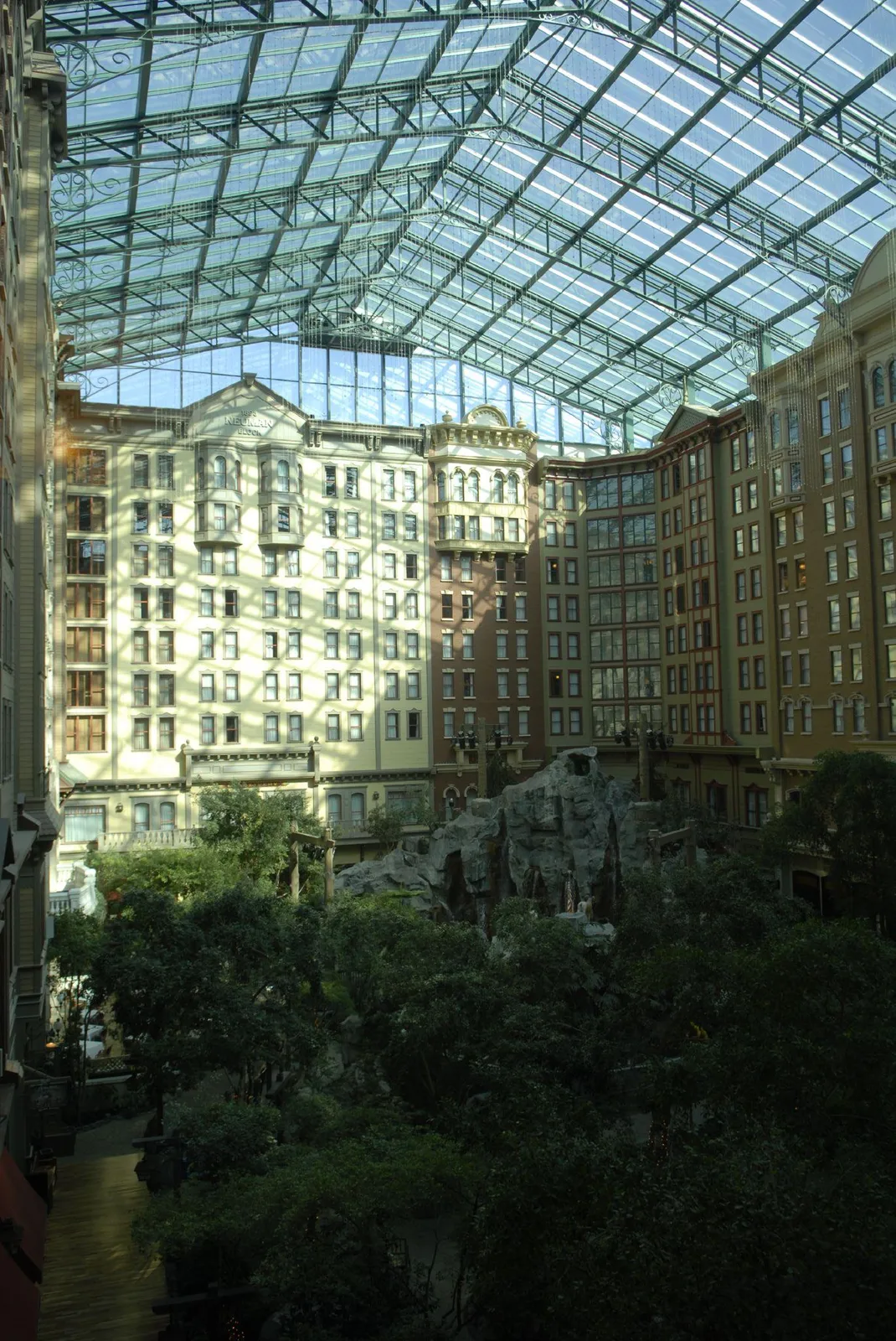 Hotel-room facades surrounding trees and artificial rockwork beneath the tall glass roof of Sam’s Town’s atrium.